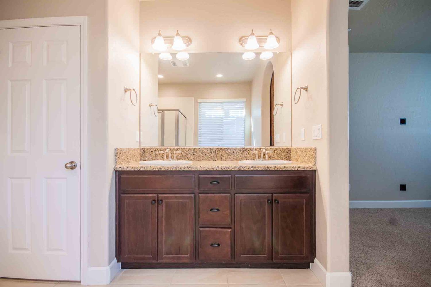 3439 Brimhall Lane Clovis, CA 93619 - Photo 23 of 43 a bathroom with a granite countertop sink a large mirror and a shower