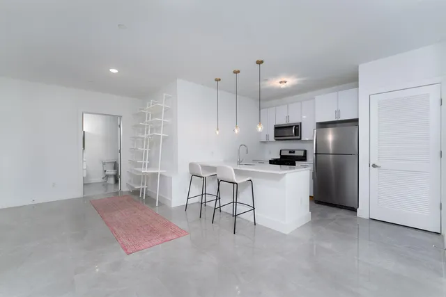 a kitchen with kitchen island white cabinets and stainless steel appliances