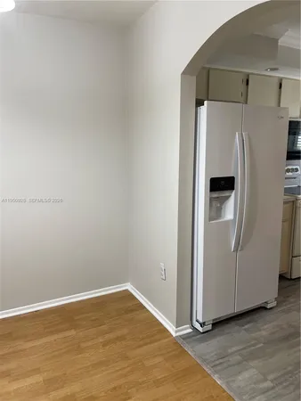 a view of a refrigerator in kitchen with stainless steel appliances wooden floor