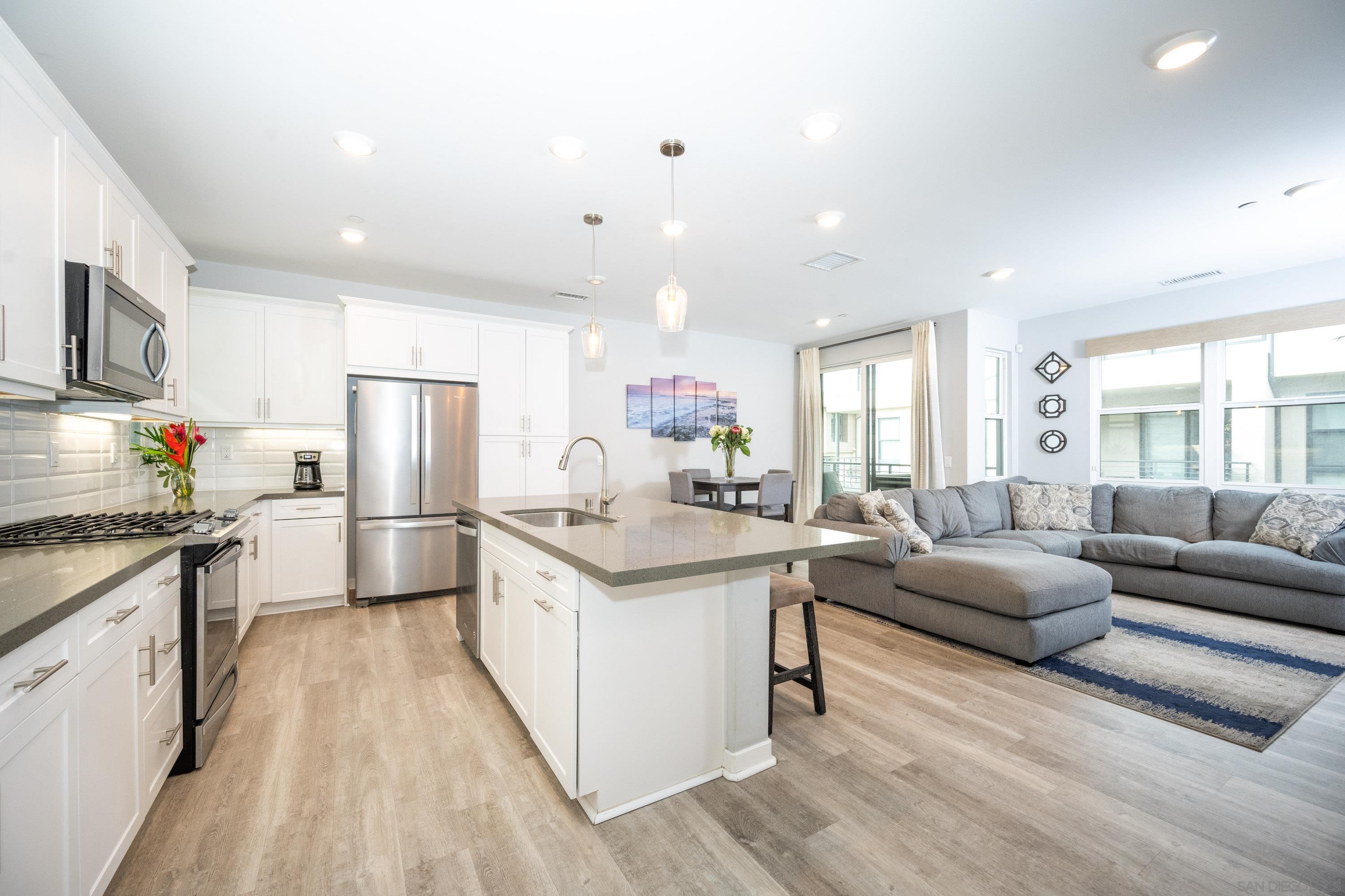 a kitchen with stainless steel appliances kitchen island granite countertop a refrigerator a sink dishwasher a stove and white countertops with wooden floor