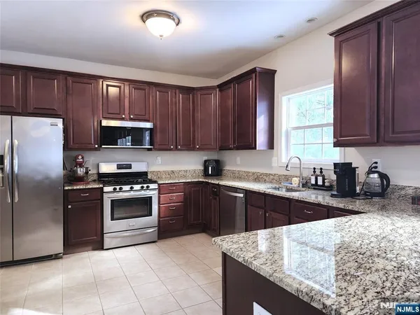 a kitchen with granite countertop stainless steel appliances a stove a sink a refrigerator a window