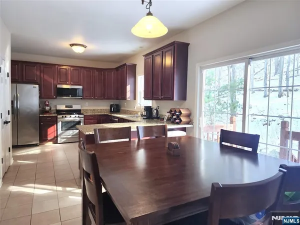a kitchen with a dining table chairs stainless steel appliances and windows