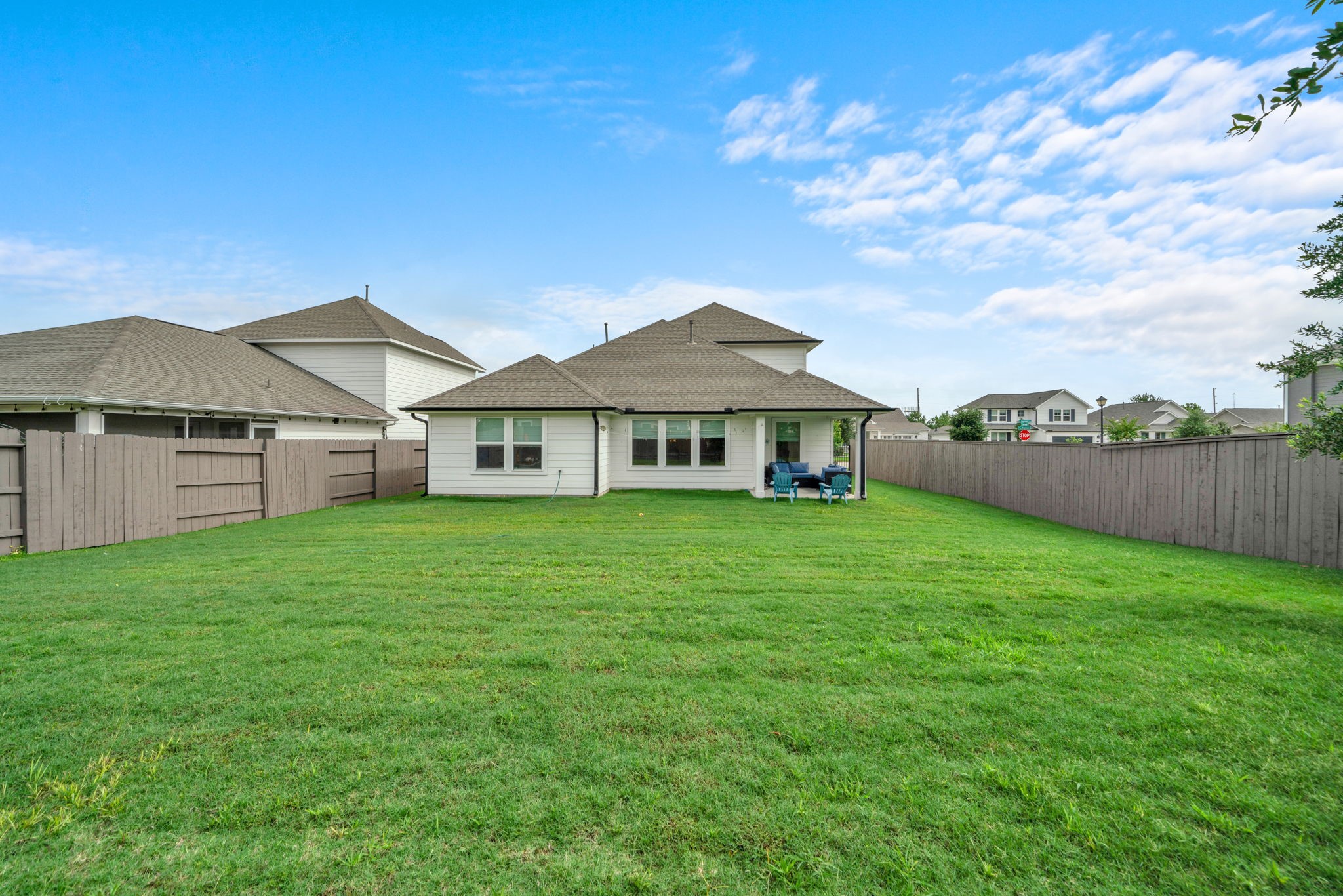 2503 Hagerman Road Conroe, TX 77384 - Photo 6 of 43 This photo shows a spacious, fenced backyard with well-maintained grass, a cozy patio area, and a view of a two-story house, perfect for outdoor activities and relaxation.
