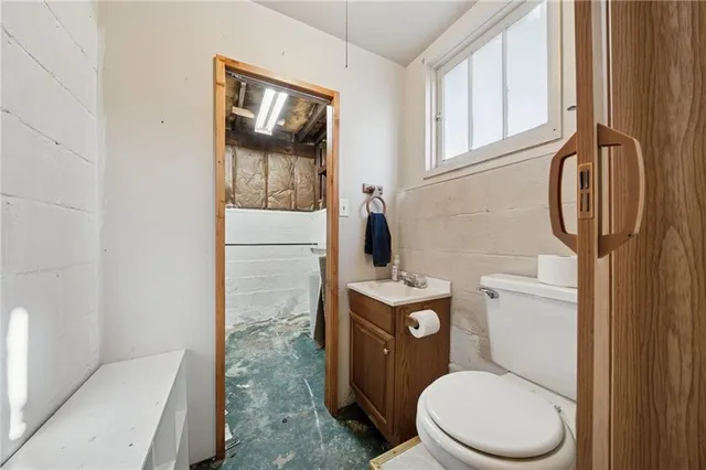 a white toilet sitting next to a bathroom sink and a mirror