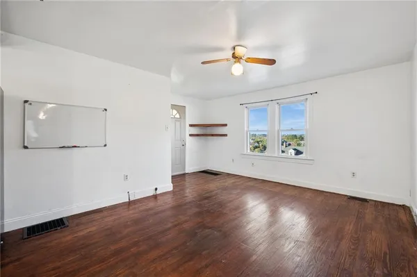 an empty room with wooden floor and windows