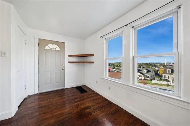 an empty room with wooden floor and window