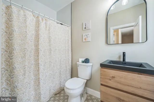 a bathroom with a granite countertop sink and a toilet