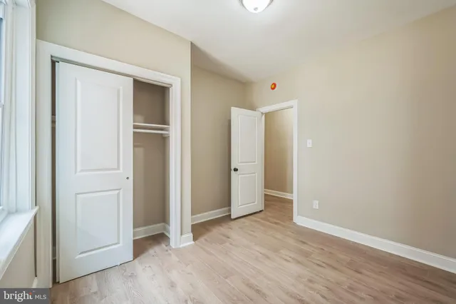 an empty room with wooden floor & closet area