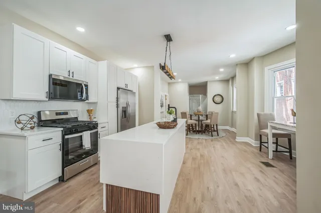 a large kitchen with sink a refrigerator and chairs