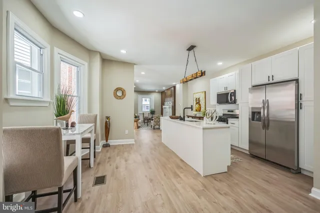 a kitchen with stainless steel appliances kitchen island wooden floors and white cabinets