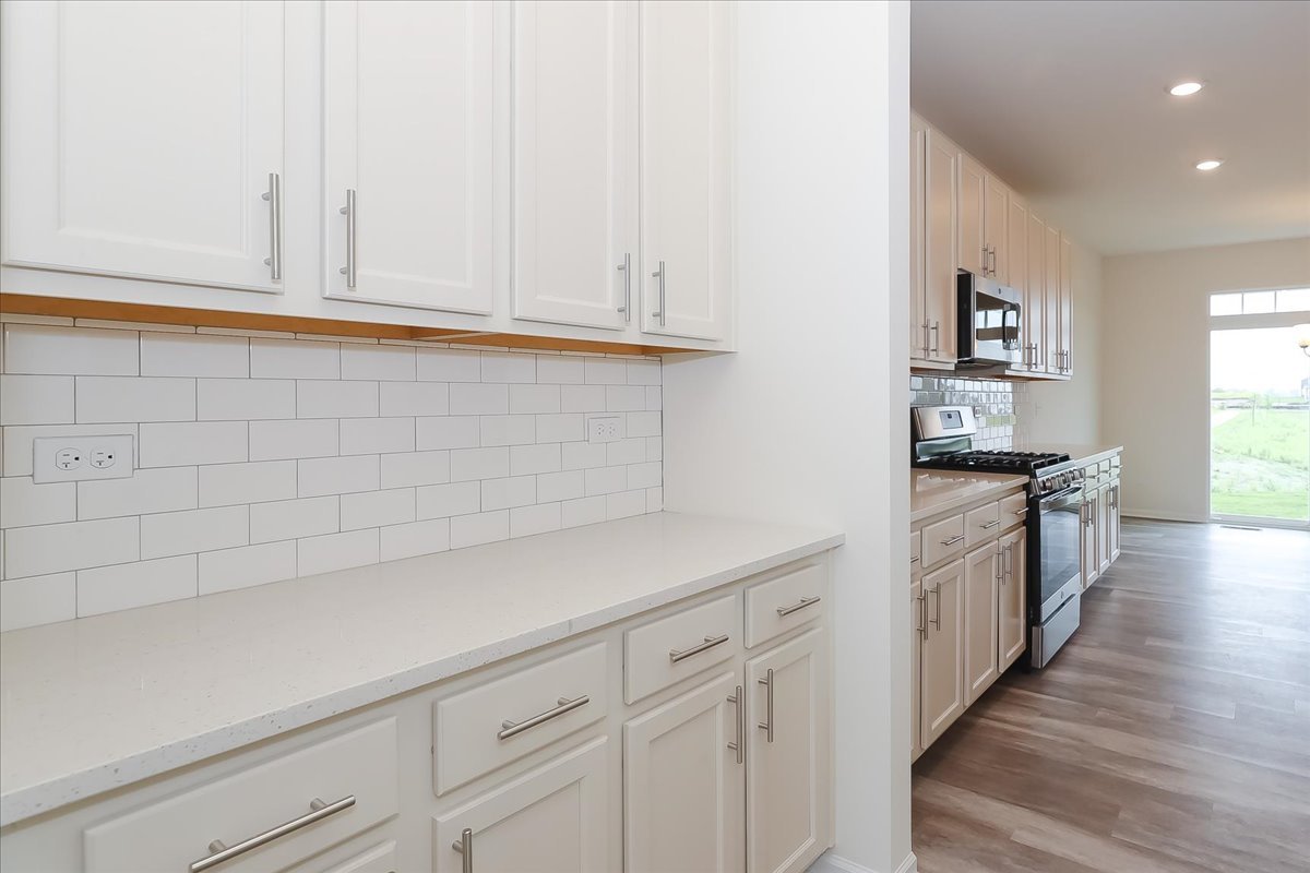 10782 Chadsey Road Huntley, IL 60142 - Photo 5 of 33 a kitchen with granite countertop white cabinets and white appliances
