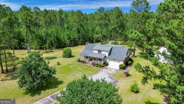 an aerial view of a house with swimming pool and large trees