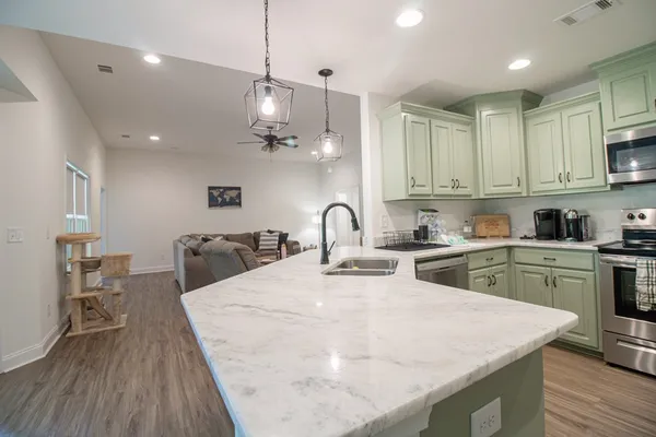 a large kitchen with kitchen island a stove a sink a center island and wooden floor