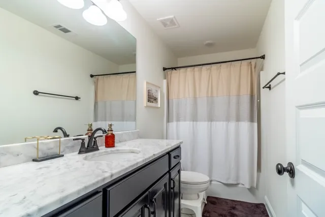 a bathroom with a granite countertop sink a toilet and shower curtain