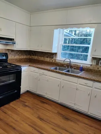 a kitchen with granite countertop white cabinets and a wooden floor