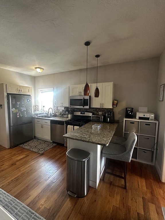 a kitchen with granite countertop a stove a sink and a refrigerator