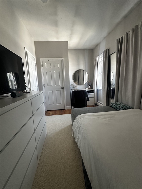 199 Athens Street, Unit 3 Boston, MA 02127 - Photo 16 of 18 a bedroom with a bed a mirror on dresser and a window