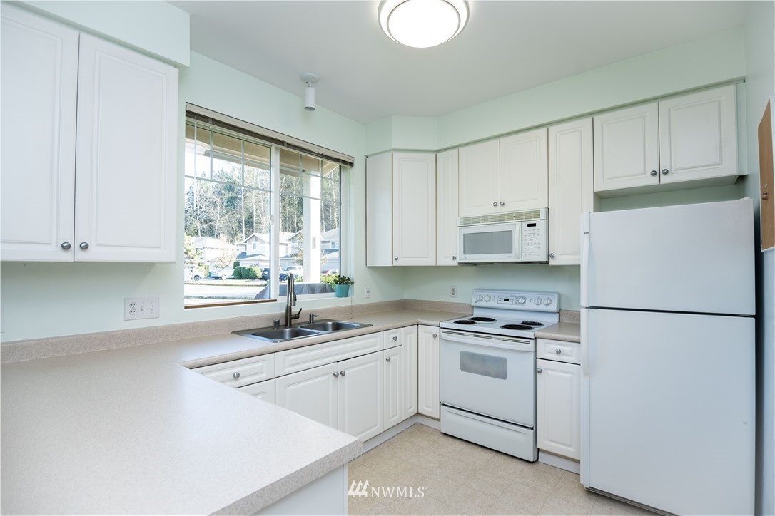 15150 140th Way Southeast, Unit G104 Renton, WA 98058 - Photo 7 of 24 a kitchen with white cabinets and white appliances