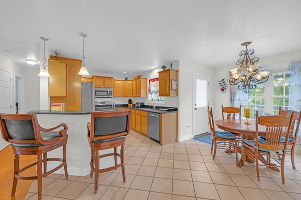 a kitchen with stainless steel appliances granite countertop a kitchen island a stove a sink a dining table and chairs