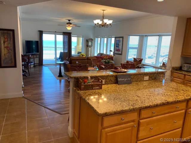 a kitchen with stainless steel appliances granite countertop a stove a refrigerator a sink a dining table and chairs with wooden floor