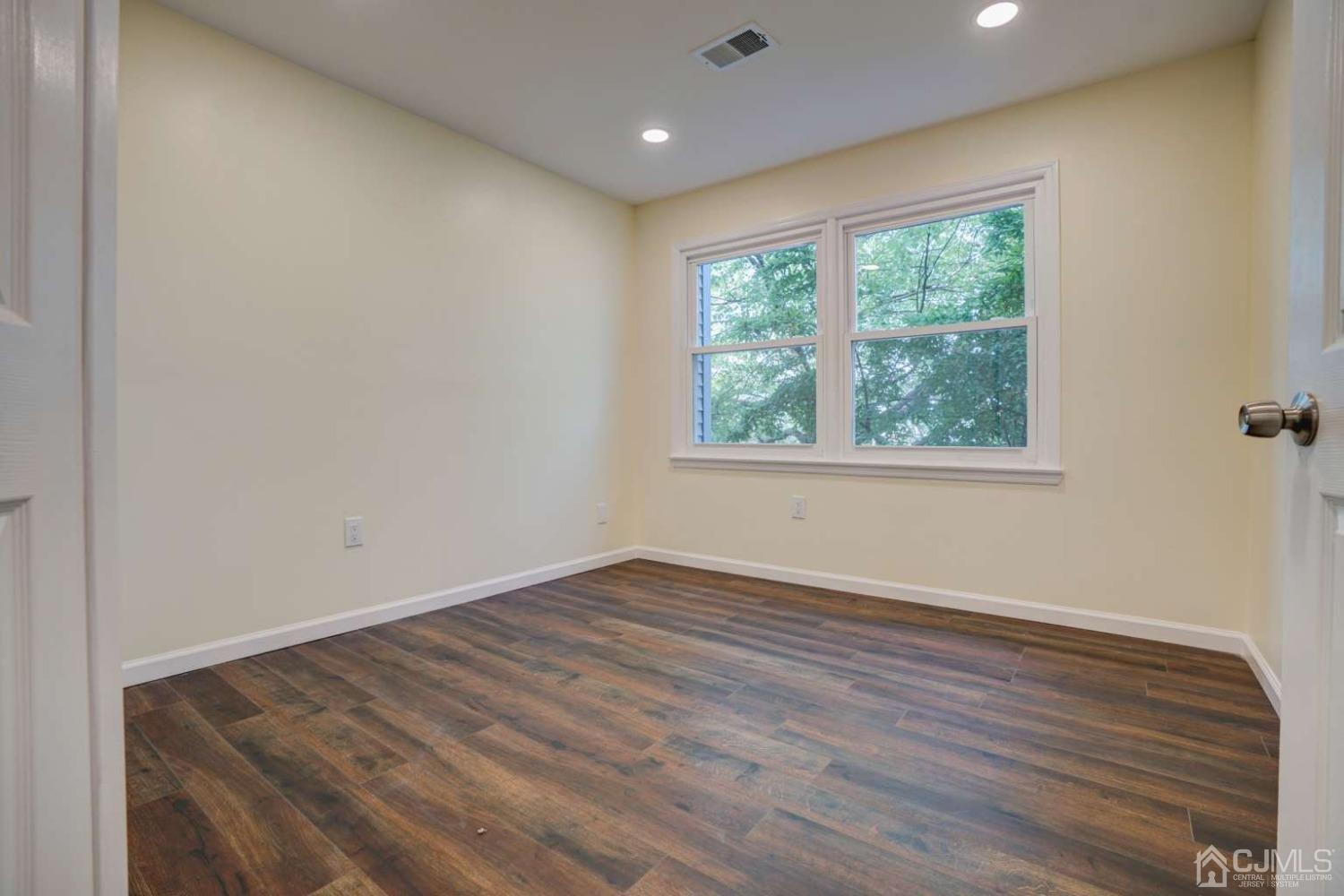 124 Edpas Road New Brunswick, NJ 08901 - Photo 16 of 24 an empty room with wooden floor and windows