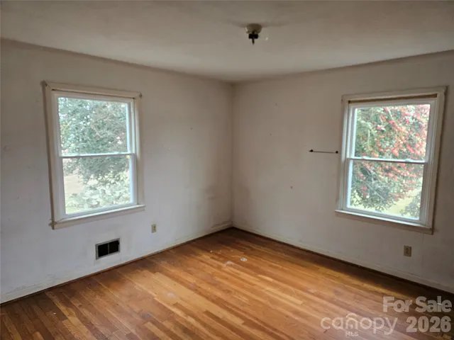 a view of an empty room with wooden floor and closet