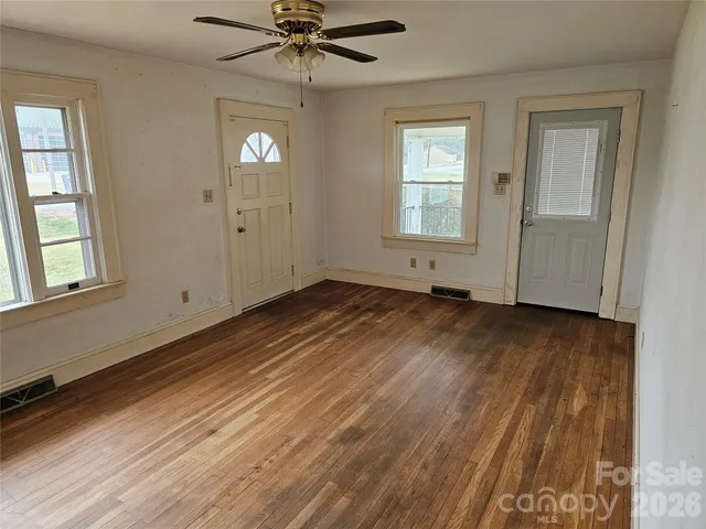 a view of an empty room with wooden floor and a window