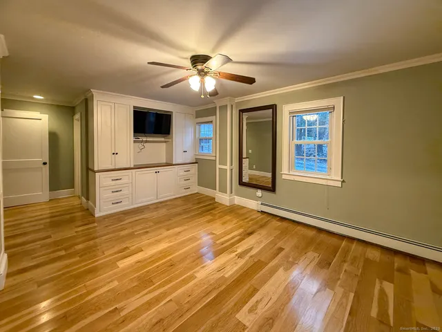 a view of empty room with wooden floor and fan