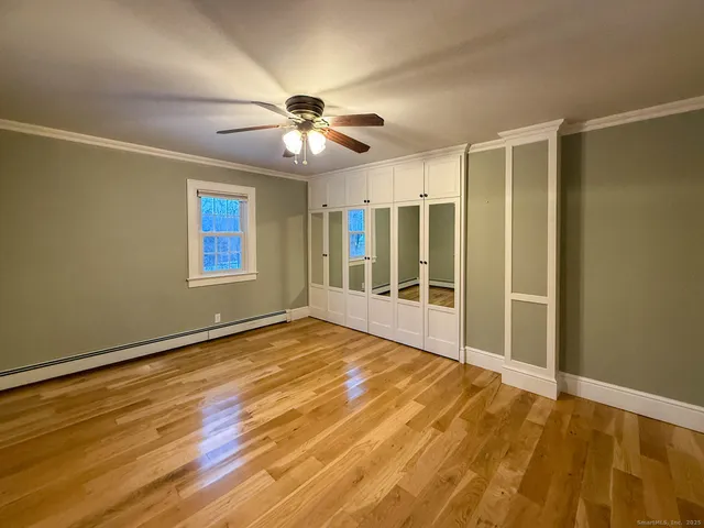 a view of an empty room with window and wooden floor