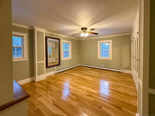 a view of an empty room with window and wooden floor