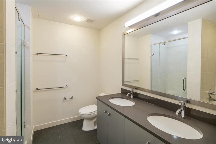 2101 Market Street, Unit 4205 Philadelphia, PA 19103 - Photo 5 of 31 a bathroom with a granite countertop sink toilet a mirror and shower