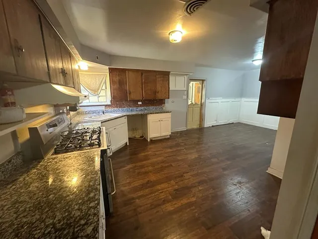 a large white kitchen with lots of counter space and wooden floor