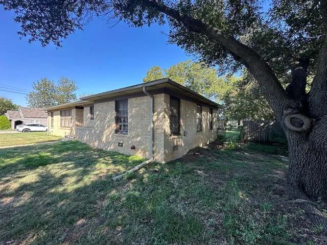 a view of a small house with a tree in the grass