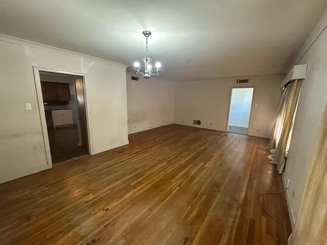 an empty room with wooden floor and chandelier