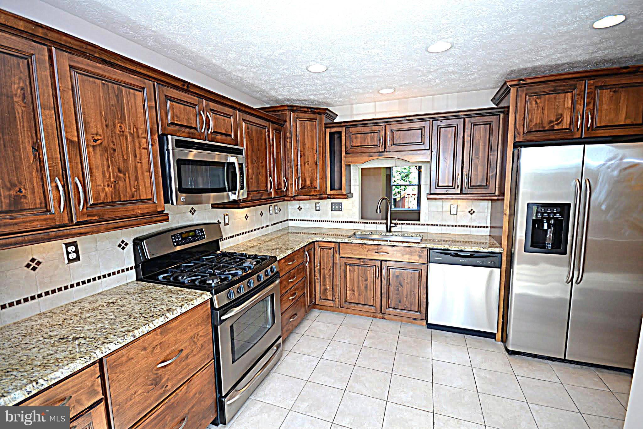9044 Constant Course Columbia, MD 21046 - Photo 2 of 10 a kitchen with stainless steel appliances granite countertop a stove top oven a sink dishwasher a refrigerator and cabinets with wooden floor