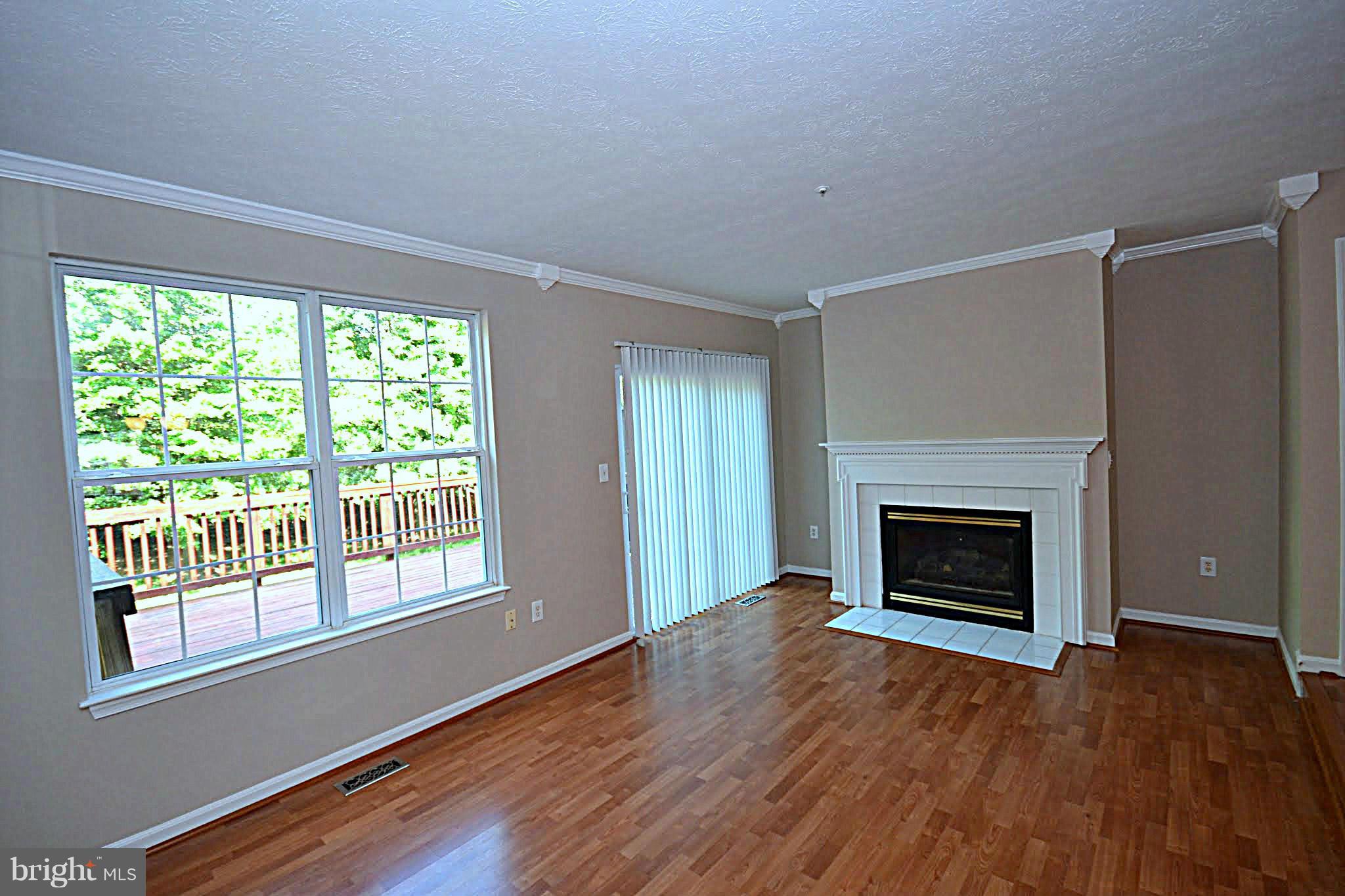 9044 Constant Course Columbia, MD 21046 - Photo 4 of 10 an empty room with wooden floor fireplace and windows