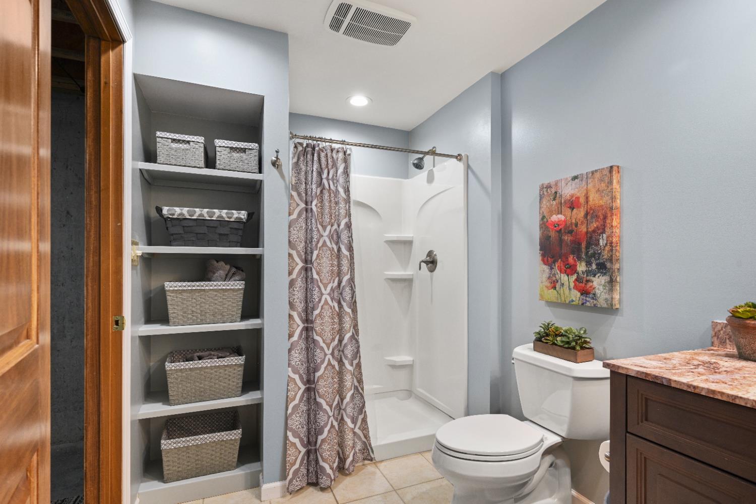 12656 Asche Road Sunman, IN 47041 - Photo 50 of 82 The basement bath features a walk-in shower, vanity with granite top, linen storage shelves and a tile floor.