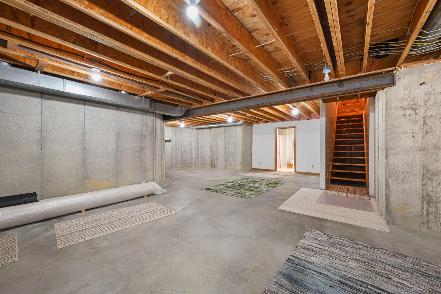 12656 Asche Road Sunman, IN 47041 - Photo 51 of 82 The open area at the bottom of the basement stairs could easily be finished into a spacious Family Room. Engineered joists allow for a space free of support posts! The far door leads into the finished full bath.