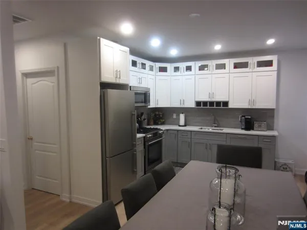 a kitchen with stainless steel appliances granite countertop a refrigerator a sink and white cabinets