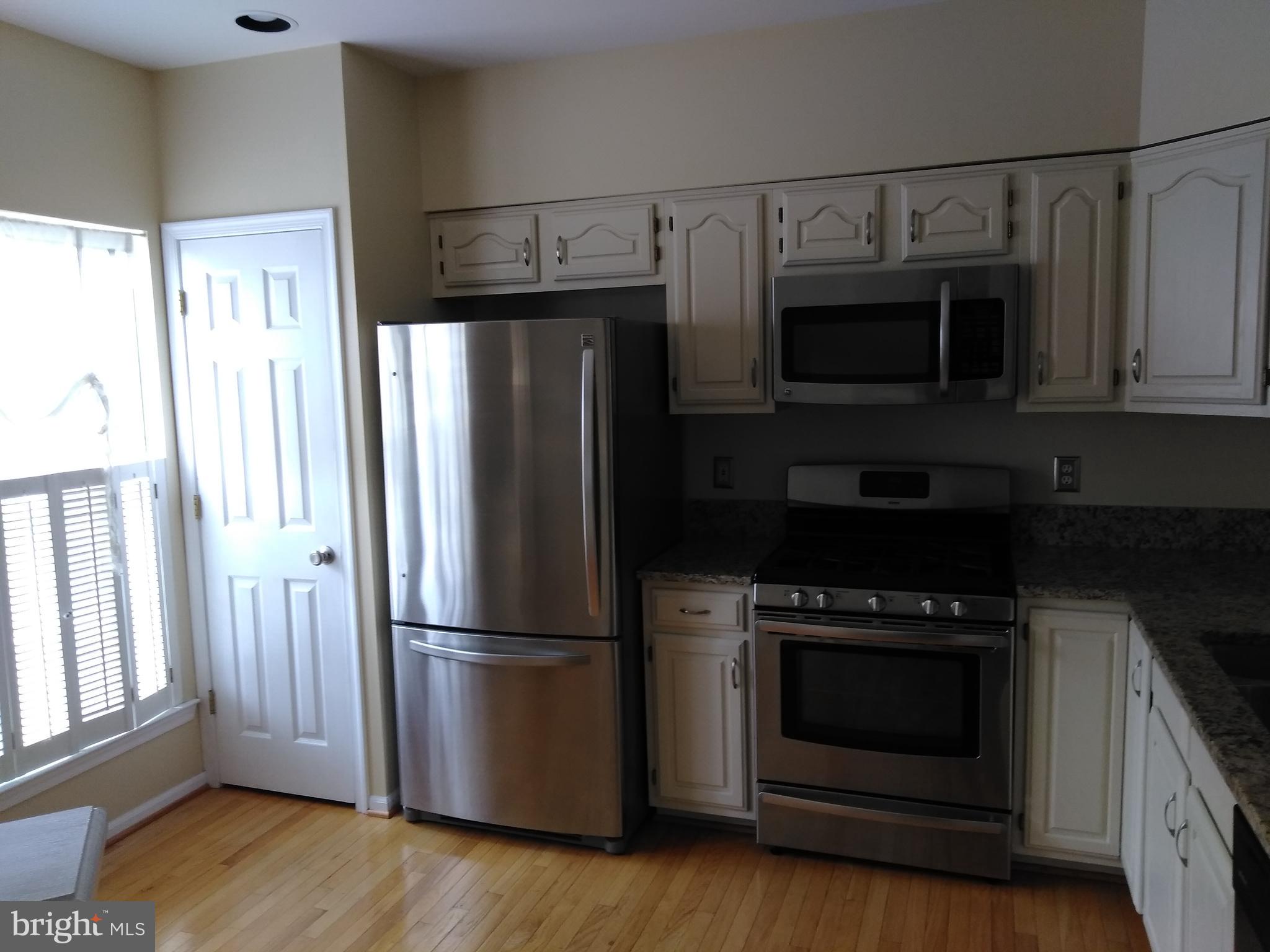 1384 Park Garden Lane Reston, VA 20194 - Photo 6 of 17 a kitchen with stainless steel appliances wooden cabinets and a wooden floor