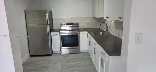 a kitchen with stainless steel appliances granite countertop a refrigerator a stove and a sink