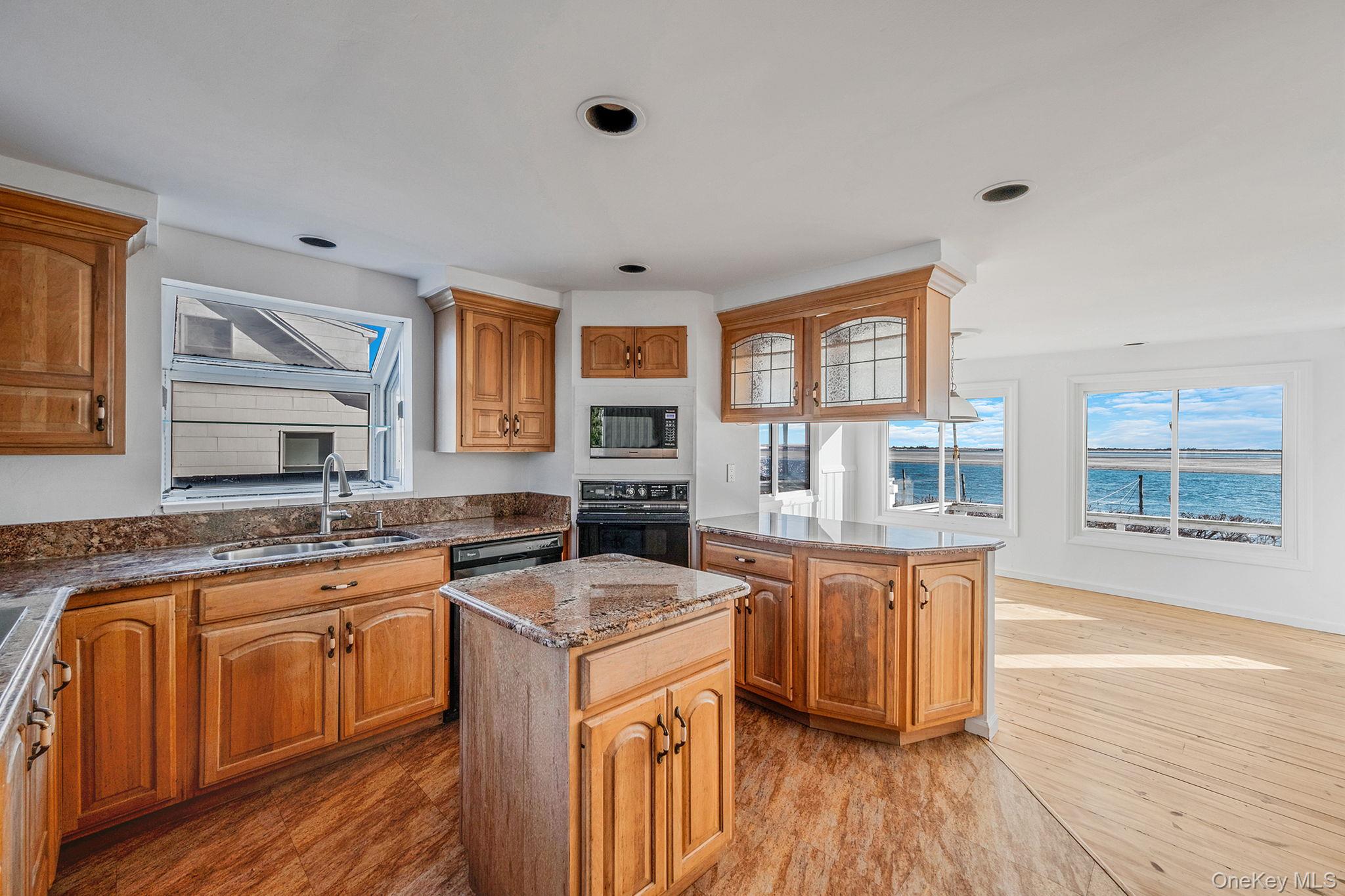 116 Oak Beach Road Babylon, NY 11702 - Photo 11 of 37 a kitchen with stainless steel appliances granite countertop a sink stove and wooden floor