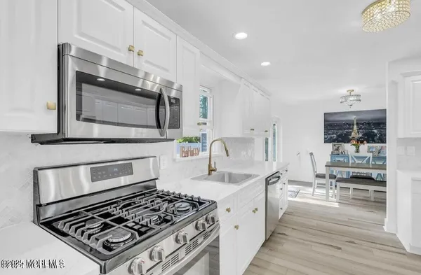 a kitchen with stainless steel appliances a stove a sink and white cabinets