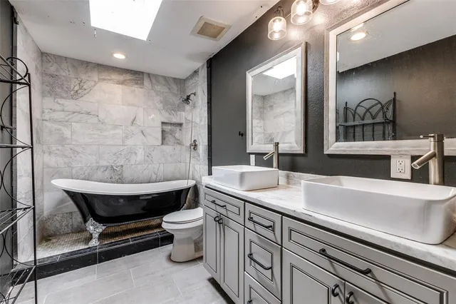 a spacious bathroom with a granite countertop sink a toilet a mirror and bathtub