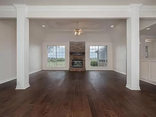 an empty room with wooden floor fireplace and windows