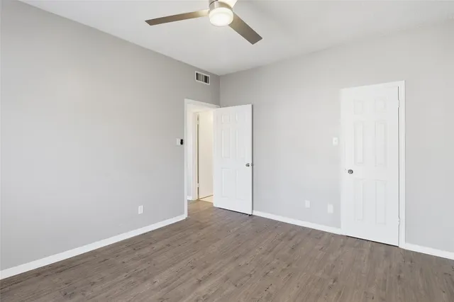 an empty room with wooden floor and ceiling fan