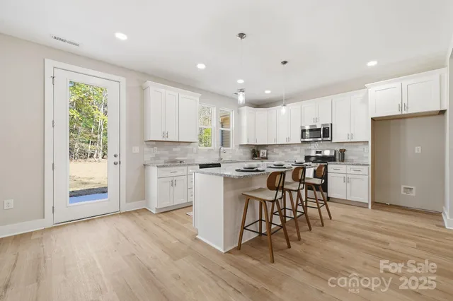 a large white kitchen with lots of counter space a sink appliances and cabinets