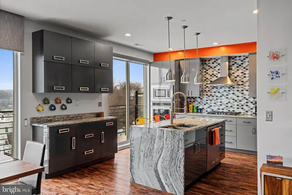 a kitchen with stainless steel appliances kitchen island granite countertop a table chairs and a refrigerator