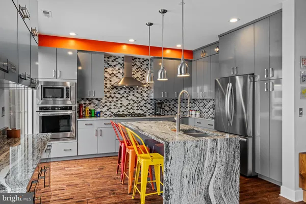 a kitchen with stainless steel appliances kitchen island granite countertop a refrigerator a stove and oven