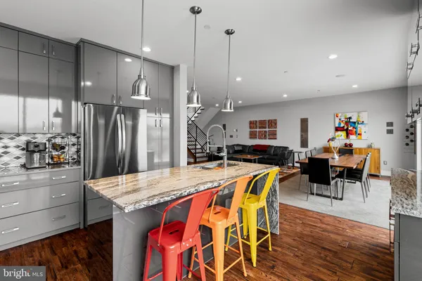 a kitchen with stainless steel appliances granite countertop a table chairs and a refrigerator